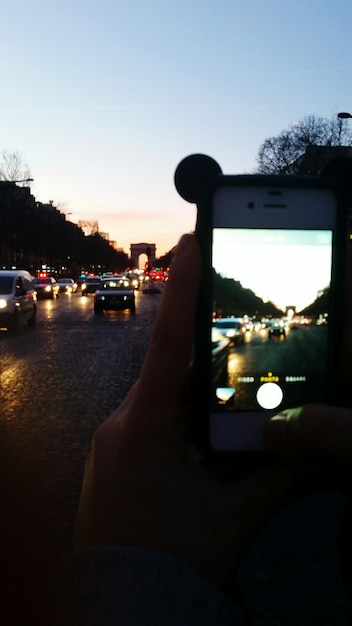 Photo close-up of hand holding car against sky during sunset