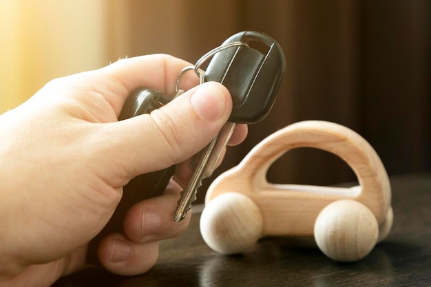 Close-up of hand holding car key on table