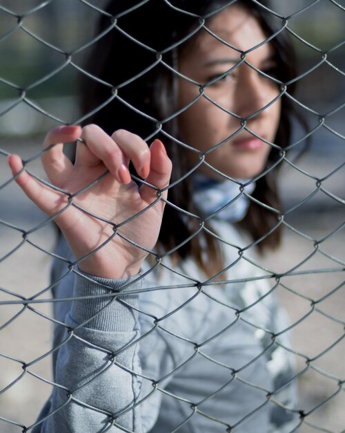 Close-up of hand holding chainlink fence