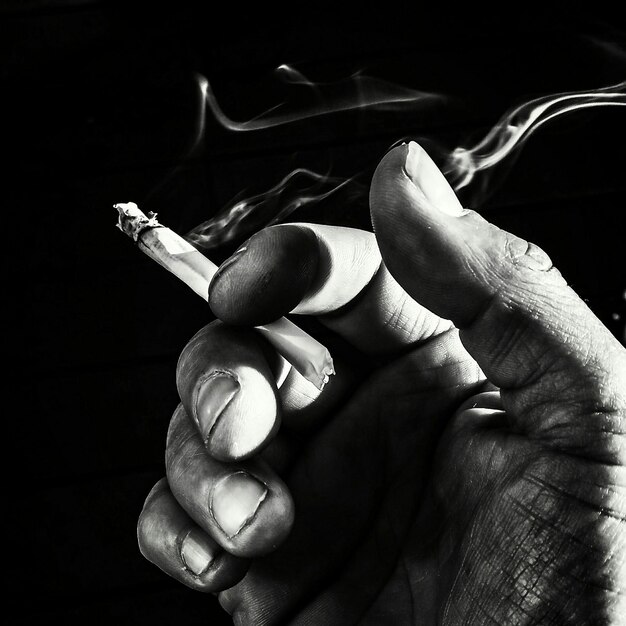 Photo close-up of hand holding cigarette