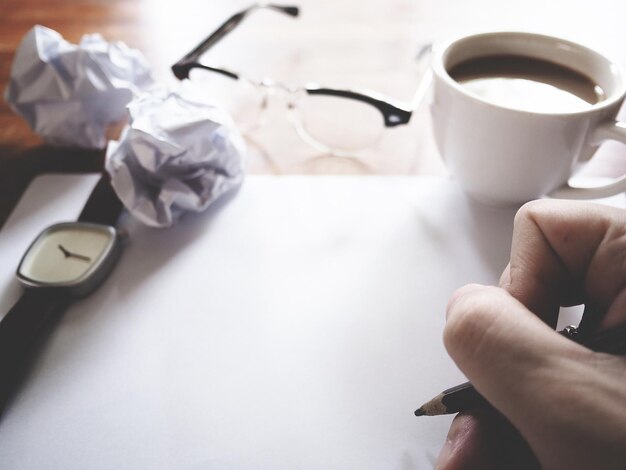 Photo close-up of hand holding coffee cup on table