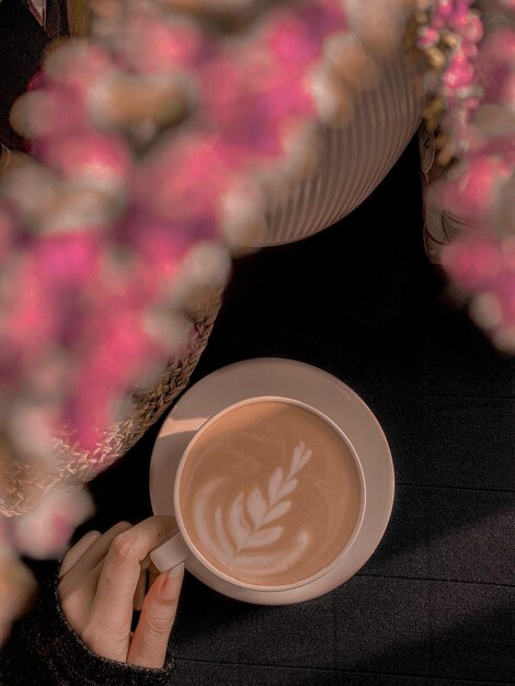 Foto close-up di una mano che tiene una tazza di caffè sul tavolo