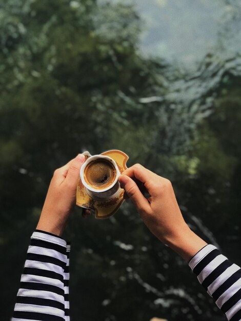 Photo close-up of hand holding coffee cup