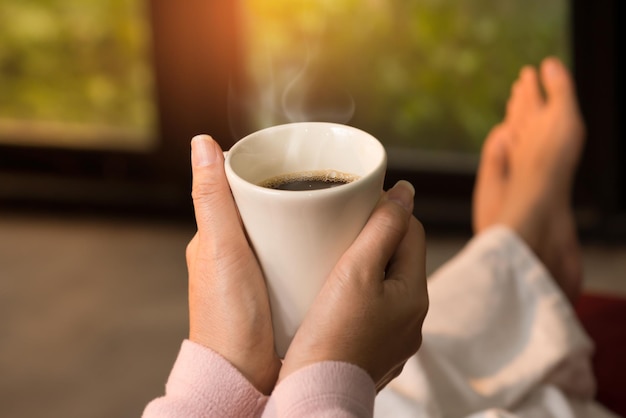 コーヒーカップを握っている手のクローズアップ