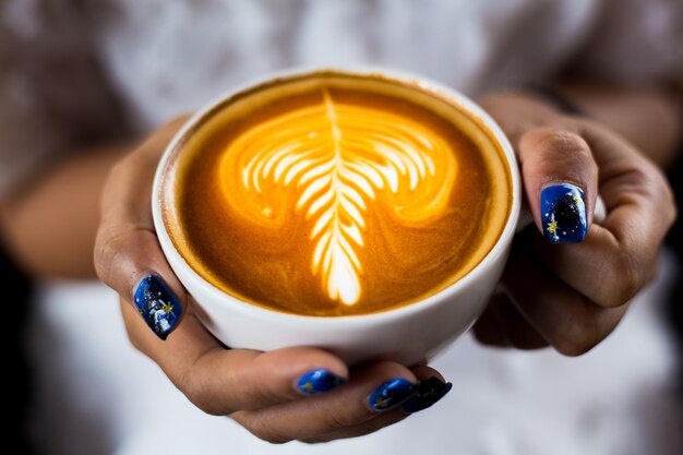 Foto close-up di una mano che tiene una tazza di caffè