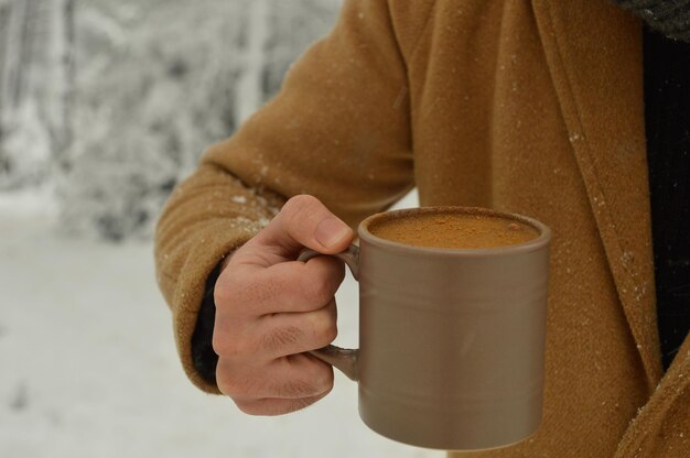 Foto close-up di una mano che tiene una tazza di caffè