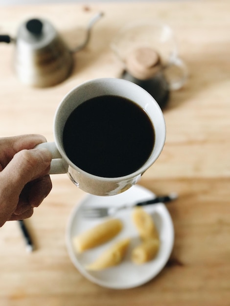 コーヒーカップを握っている手のクローズアップ