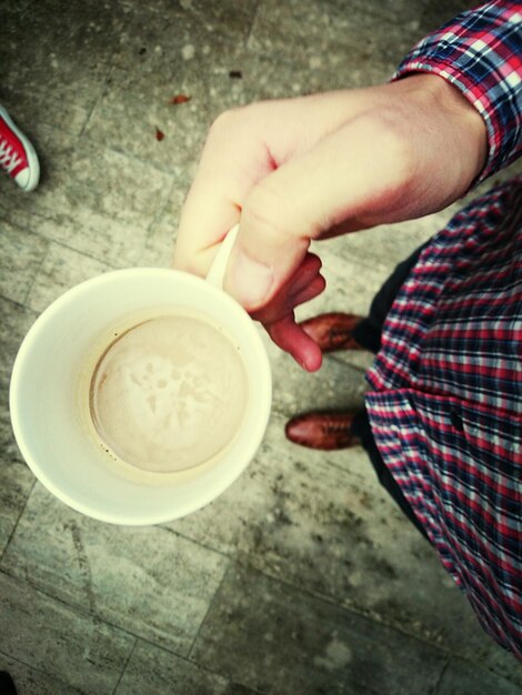 Foto close-up di una mano che tiene una tazza di caffè