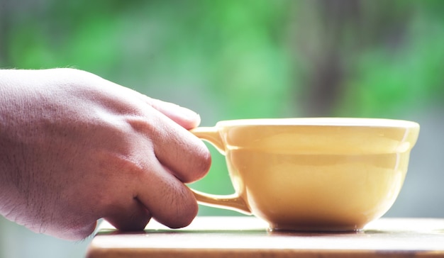 Foto close-up di una mano che tiene una tazza di caffè