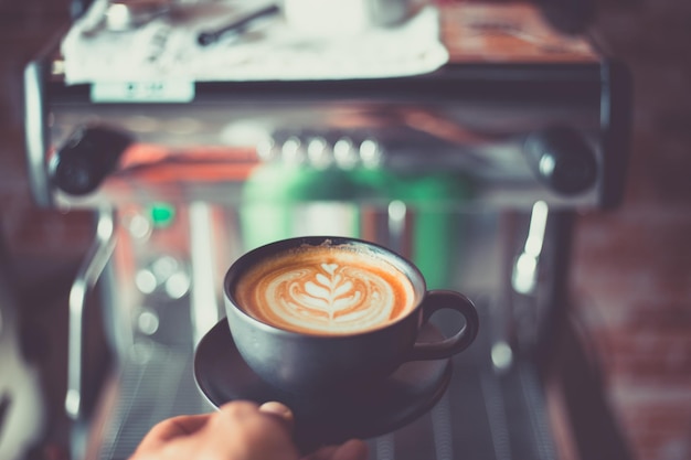 Close-up of hand holding coffee on table