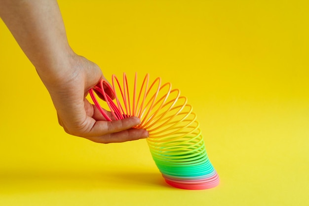 Photo close-up of hand holding coiled spring against yellow background