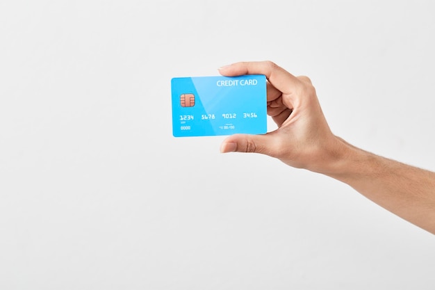 Close-up of hand holding credit card against gray background