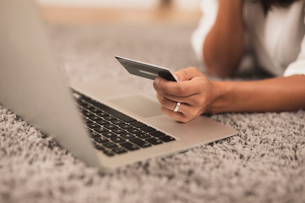 Photo close-up hand holding a credit card next to a laptop