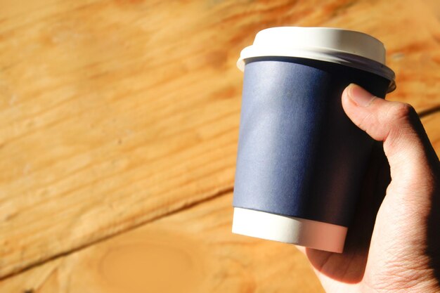 Close-up of hand holding disposable cup