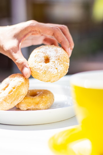 Photo close-up of hand holding donut in plate
