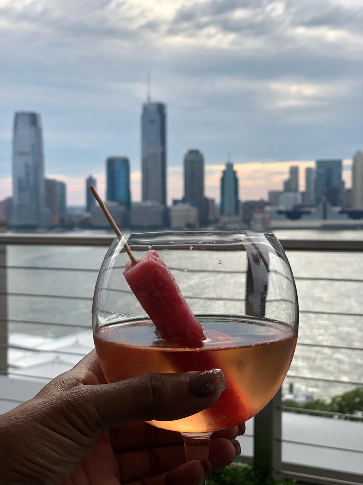 Photo close-up of hand holding drink against buildings in city