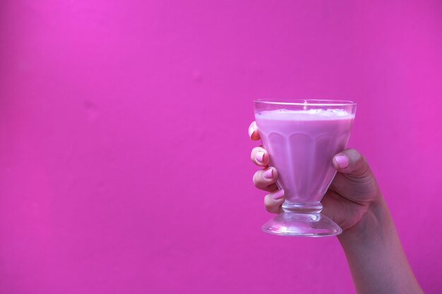 Close-up of hand holding drink against pink background