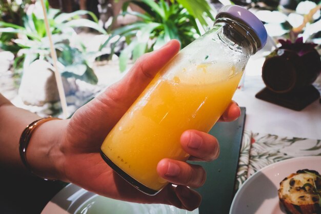 Photo close-up of hand holding drink on table