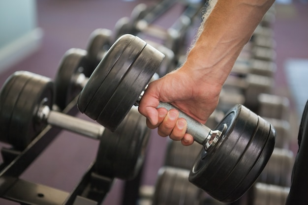 Chiuda in su della mano che tiene il dumbbell in palestra