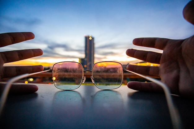 Photo close-up of hand holding eyeglasses against sky