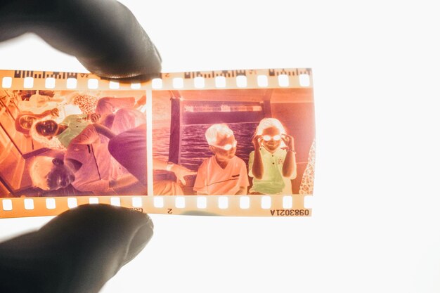 Photo close-up of hand holding film negative against white background