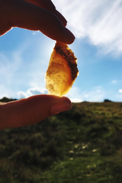 Photo close-up of hand holding food against sky