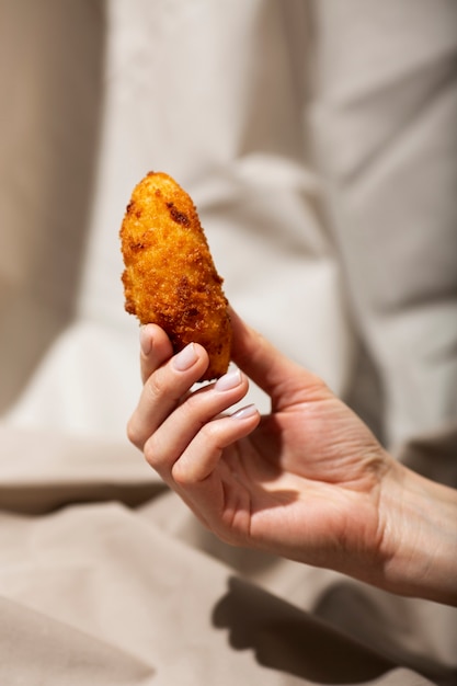 Close up hand holding food croquette