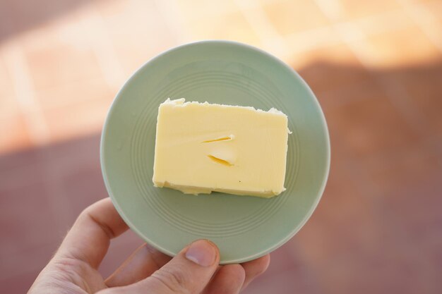 Close-up of hand holding fresh butter on plate