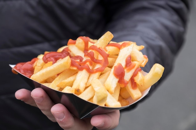 Photo close-up of hand holding fries