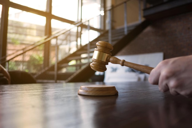 Photo close-up of hand holding gavel over sounding block on table