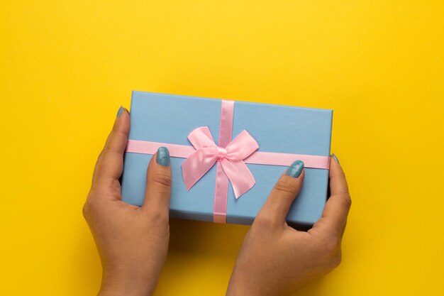 Close-up of hand holding gift against yellow background