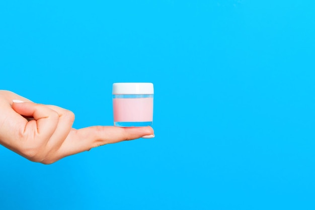 close-up of hand holding glass against blue background
