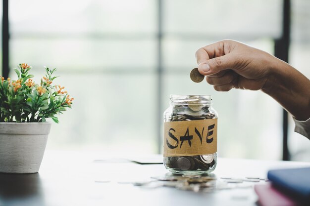 Photo close-up of hand holding glass jar on table