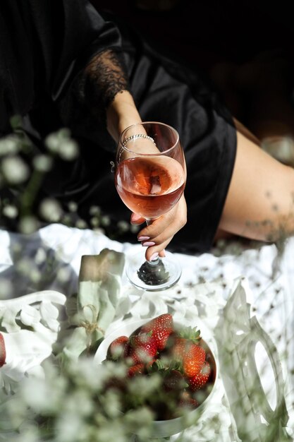 Foto close-up di una mano che tiene un bicchiere di vino rosato