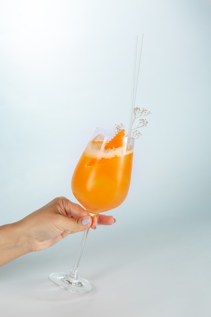 Close up of a hand holding a glass of Singapore cocktail on white  with copy space.