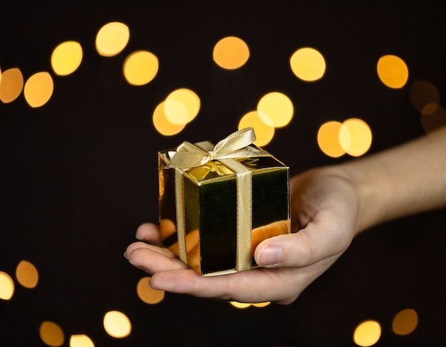 Close up of a hand holding a golden gift box