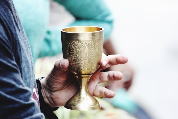 close-up of hand holding golden goblet