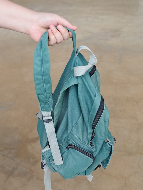 Photo close up of hand holding green fabric backpack. made from fine canvas.