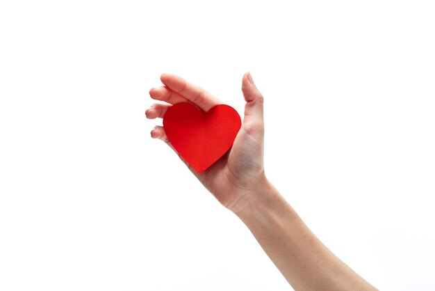 Foto close-up di una mano che tiene carta a forma di cuore su uno sfondo bianco