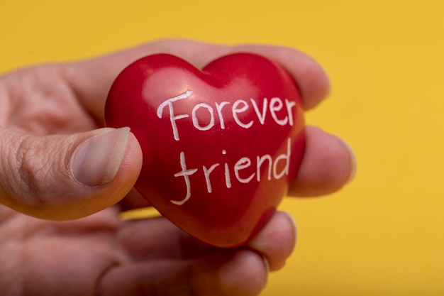 Photo close-up of hand holding heart shape with text against yellow background