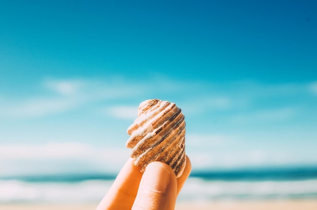 Photo close-up of hand holding ice cream against beach