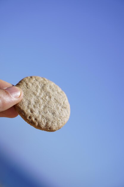 Close-up of hand holding ice cream against blue sky