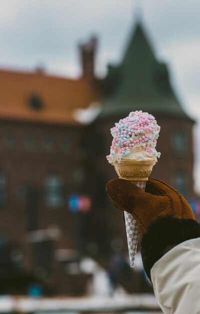 Foto close-up di una mano che tiene il gelato contro uno sfondo sfocato