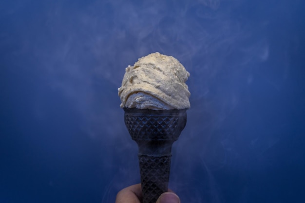 Foto close-up di una mano che tiene il gelato contro uno sfondo sfocato