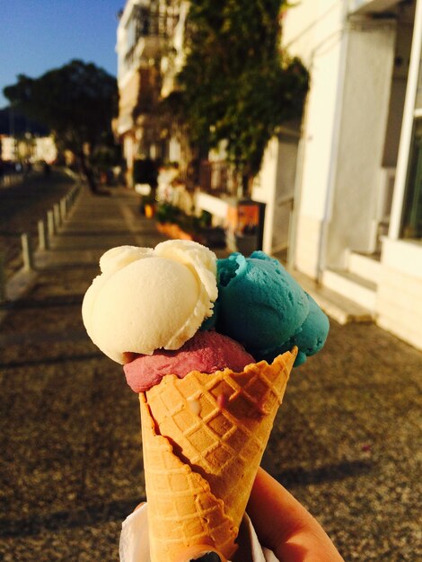 Photo close-up of hand holding ice cream cone