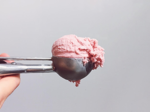 Close-up of hand holding ice cream over white background