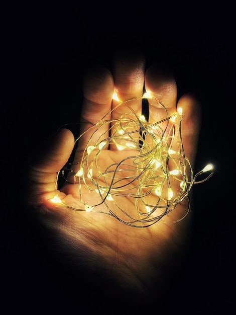 Close-up of hand holding illuminated string lights