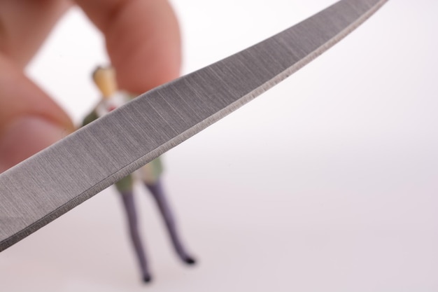 Photo close-up of hand holding knife and figurine against white background