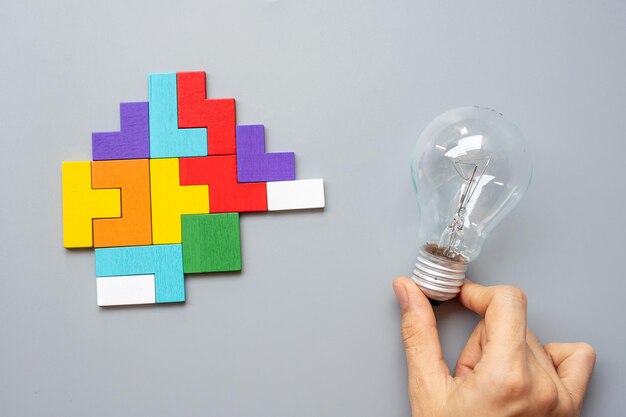 Close-up of hand holding light bulb over white background