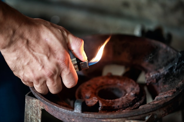 Close up hand holding lighter over old gas